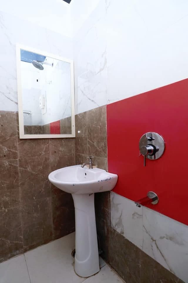 Attached bathroom with pedestal washbasin, mirror and shower fittings