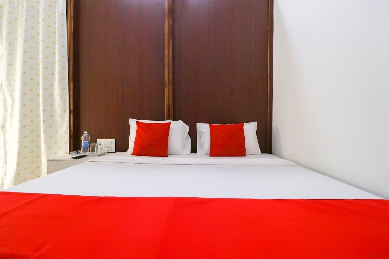 Made-up double bed with tall wooden headboard in a guest room