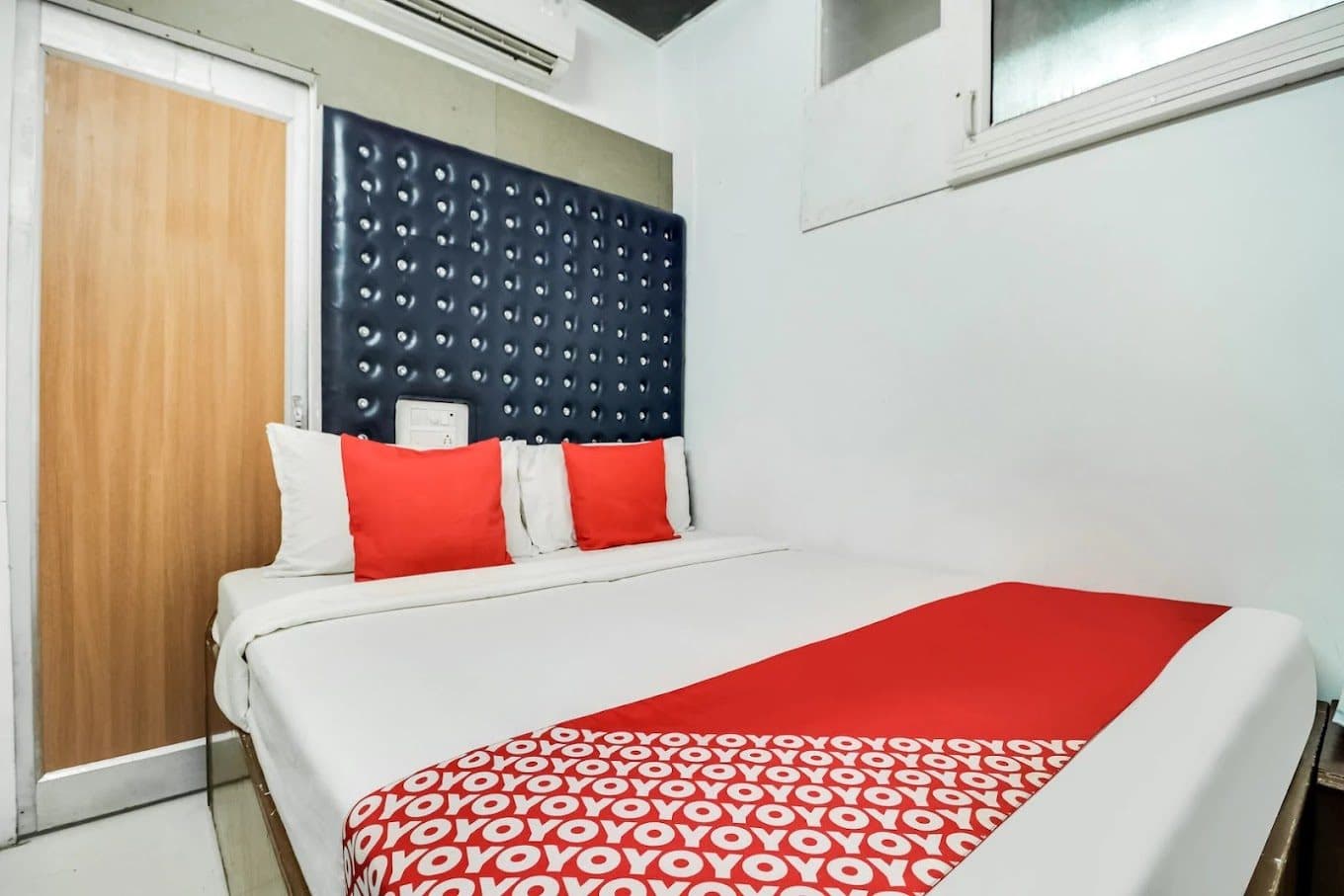 Compact guest room with padded navy headboard and air conditioning